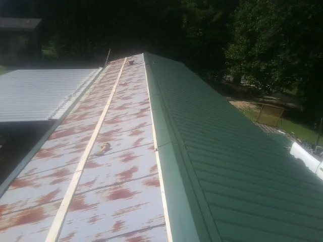 Old rusted panels beside newly installed green metal roofing — Wind Damage Roof Repair by Roofing Brothers in Havre De Grace