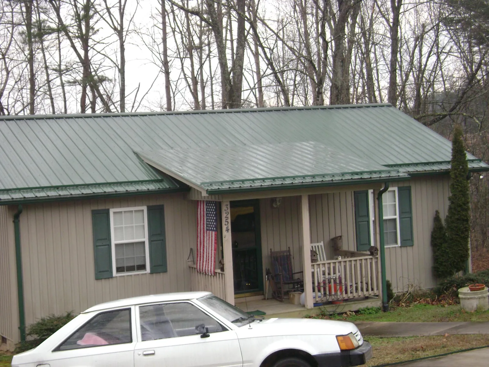 Green metal roof and front porch on a tan sided cottage in Havre De Grace