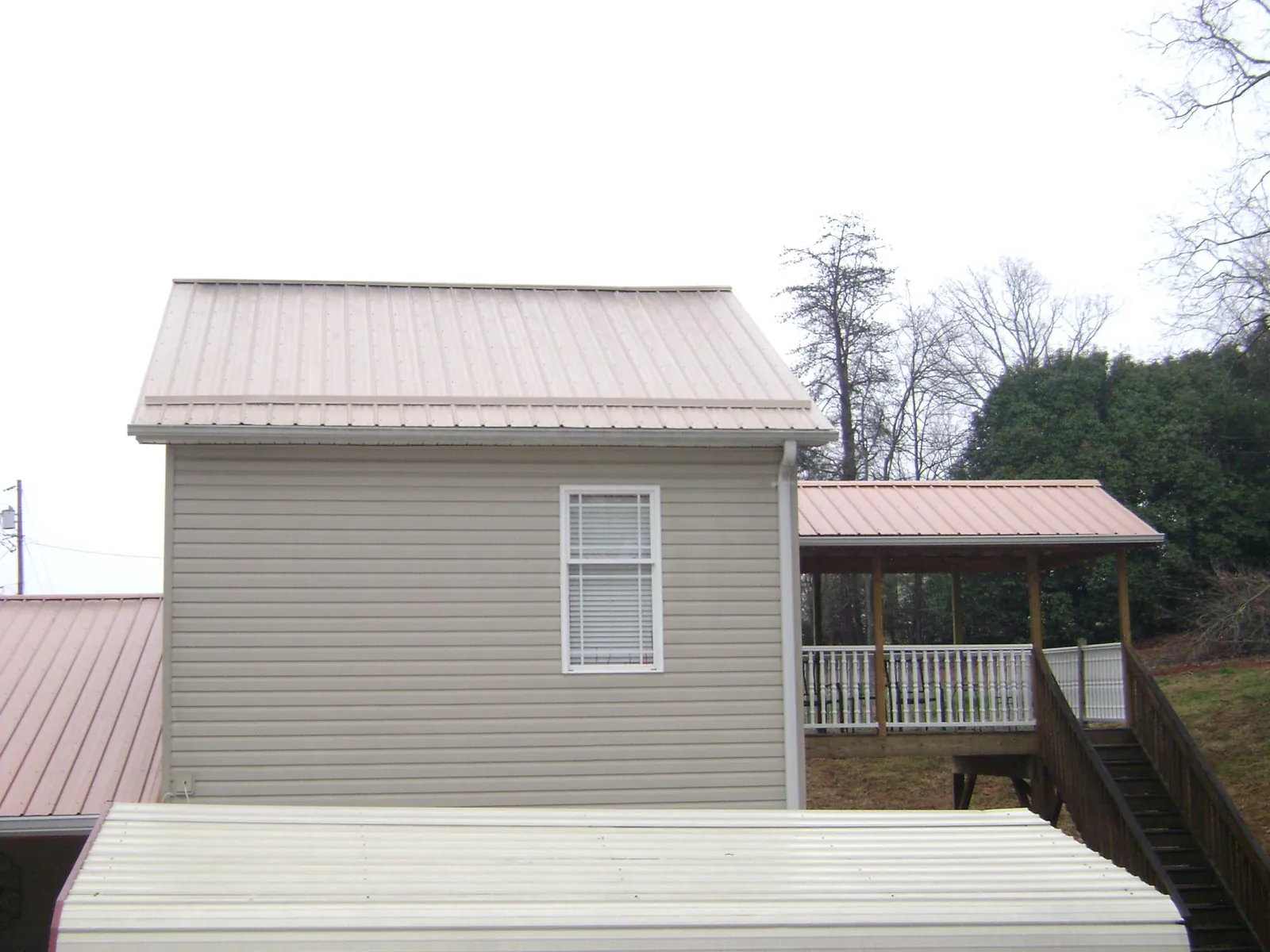 Tan metal roofs on a two story addition and attached porch, from a Roof Replacement job in Havre De Grace