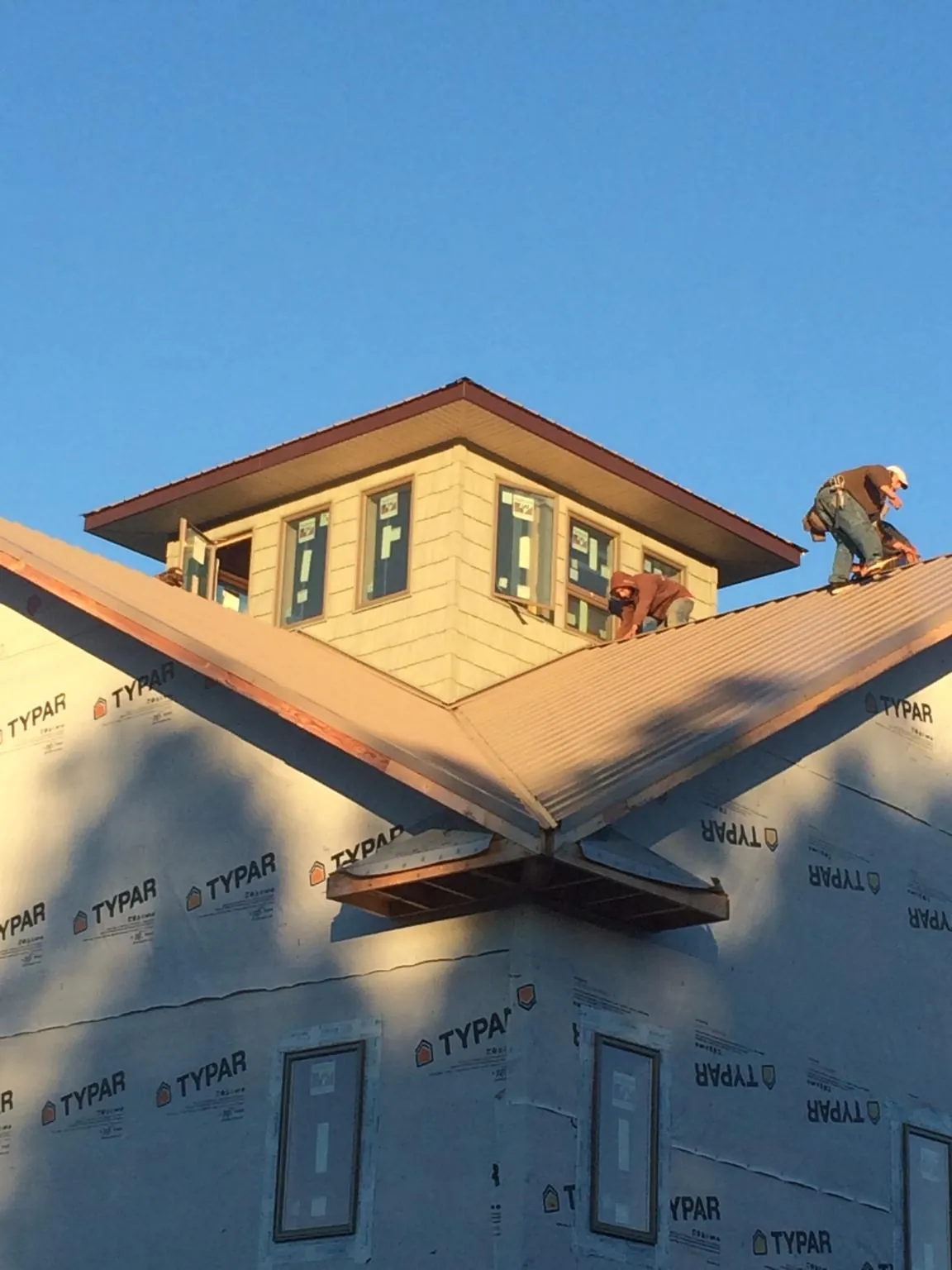 Roofers working around a rooftop cupola on a new metal roof at sunset — Roof Waterproofing in Havre De Grace by Roofing Brothers